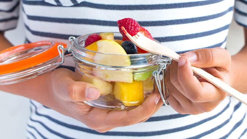 用叉子在罐子里吃水果的手特写